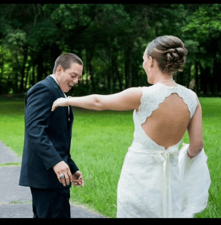 a bride and groom are posing for a picture and the back of the bride 's dress is visible