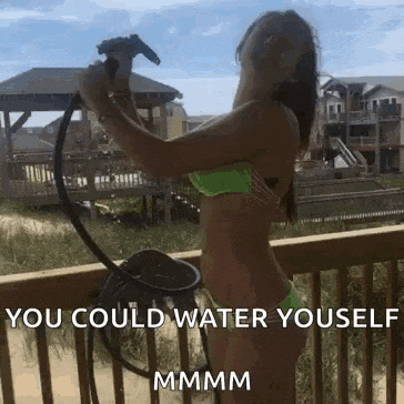 a woman in a bikini is spraying herself with a hose on a deck .