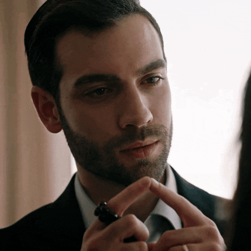 a man with a beard is holding a black ring in his hand