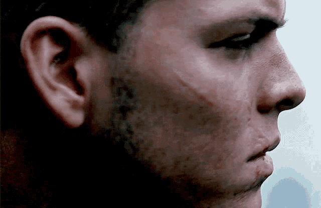 a close up of a man 's face with a scar on his cheek