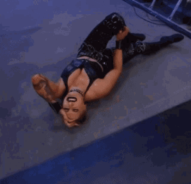 a female wrestler is laying on the floor with her hands on her face