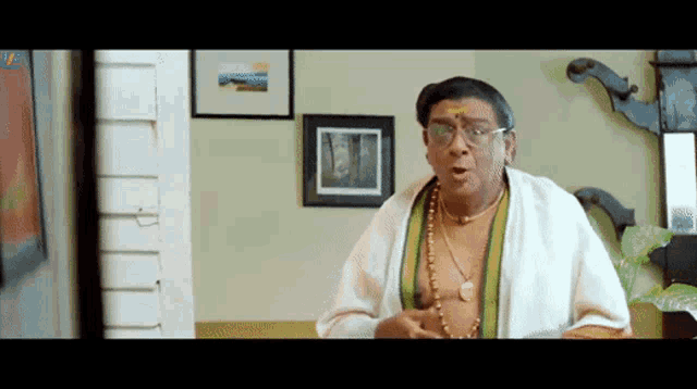 a man with glasses and a necklace is making a funny face in a room
