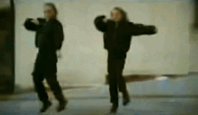 a blurry picture of two men dancing in front of a wall