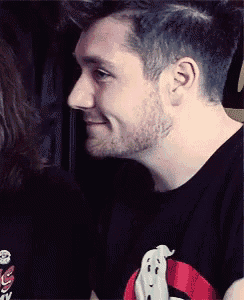a man wearing a black shirt with a ghost on it is smiling