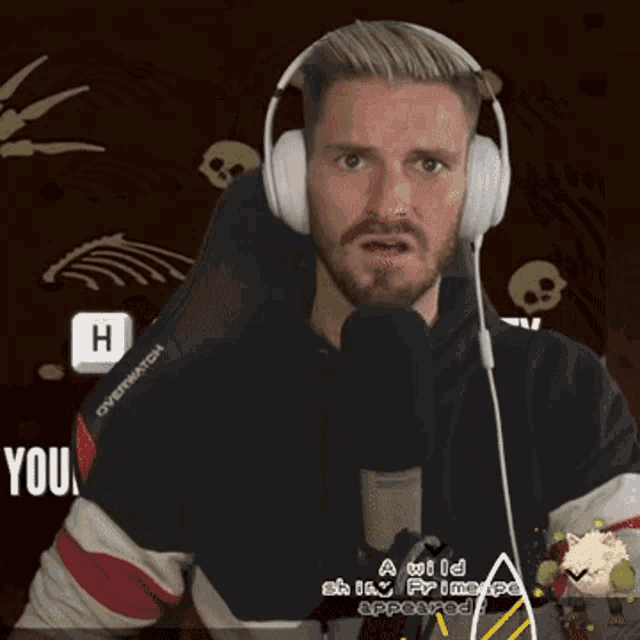 a man wearing headphones and a black overwatch shirt
