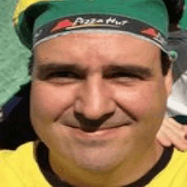 a man wearing a yellow shirt and a green hat is smiling .