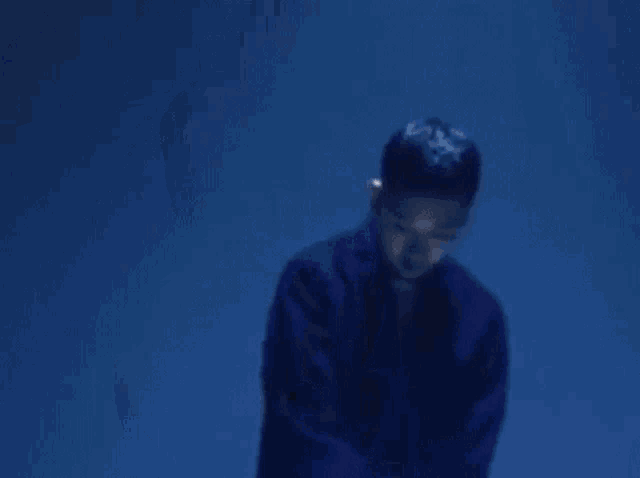 a man in a blue jacket is holding a white plate in his hand in a dark room .