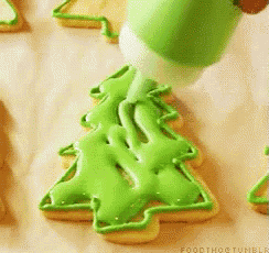 a person is decorating a cookie in the shape of a christmas tree