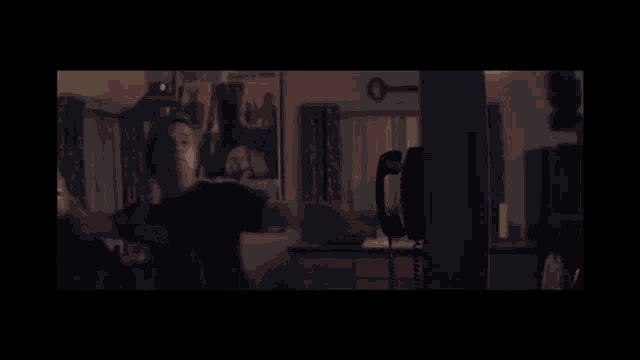a woman is standing in a dark room with a poster on the wall that says ' a man '