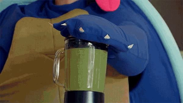 a person in a monster costume is making a green smoothie in a blender
