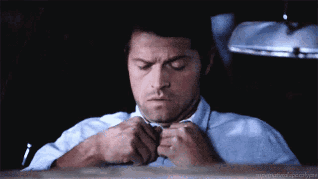 a man is adjusting his tie in a dark room with the words supernatural apocalypse below him