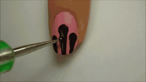 a woman 's nails are painted pink and black with a green tip