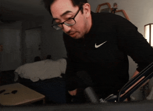 a man wearing glasses and a black nike sweatshirt