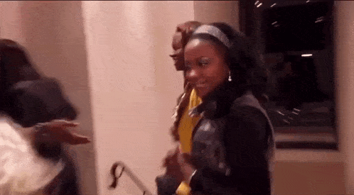 a group of people are standing next to each other in a room and dancing .
