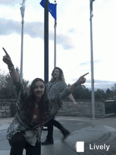 a man and a woman are dancing in front of a flag pole with the word lively in the corner