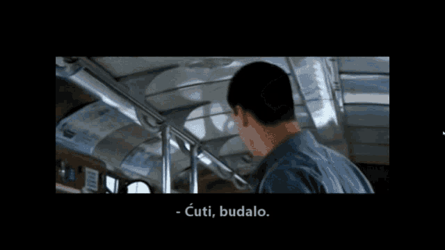 a man in a blue shirt is talking to another man on a bus