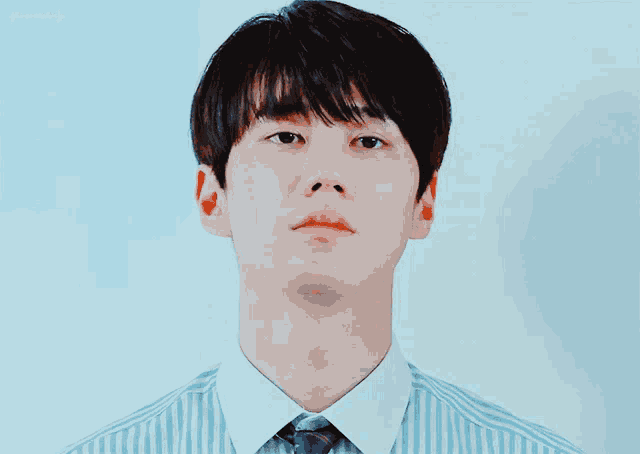 a man wearing a blue and white striped shirt and tie looks at the camera