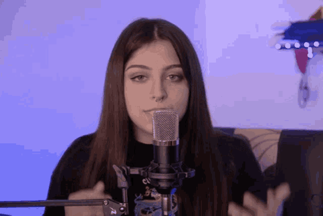 a young woman stands in front of a microphone with a dragon on her shirt
