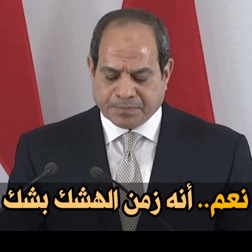 a man in a suit and tie is giving a speech in front of a red white and blue flag