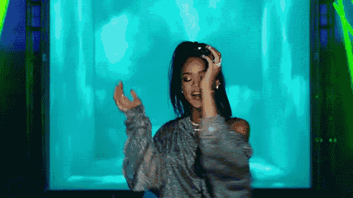 a woman is dancing on a stage in front of a blue screen .