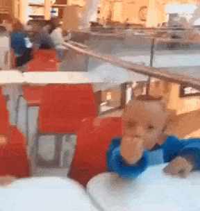 a baby is sitting at a table in a restaurant eating a sandwich .