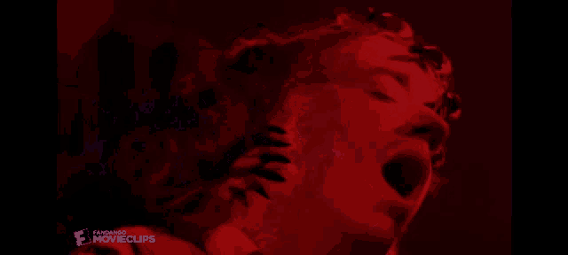 a close up of a person 's face with a red background that says movieclips on the bottom