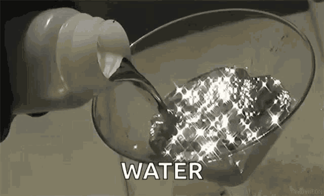 a bottle of water is being poured into a glass filled with water .