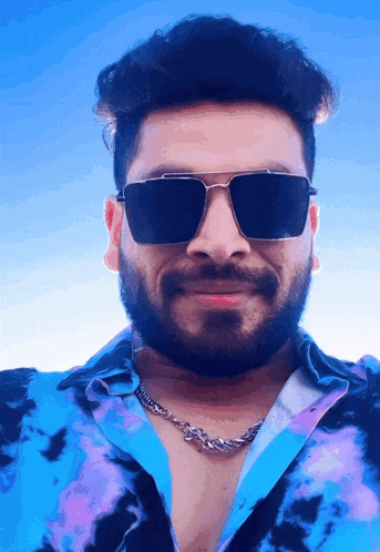 a man with a beard wears sunglasses and a blue shirt