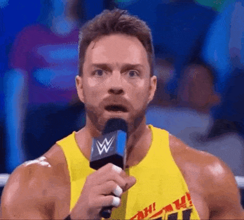 a wrestler is holding a microphone and making a funny face .