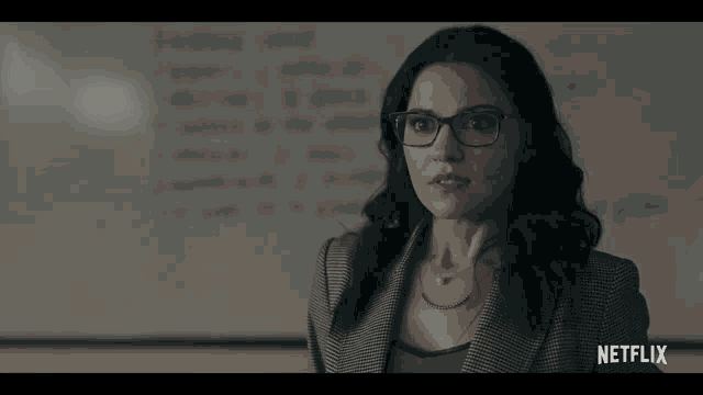 a woman wearing glasses stands in front of a white board with the word netflix on the bottom