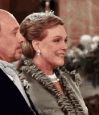 a man and a woman are sitting next to each other and the woman has a tiara on her head .