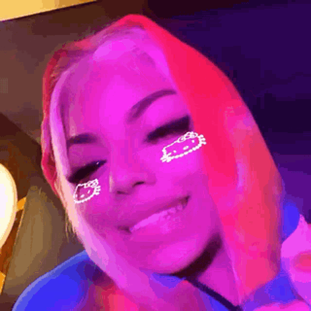 a girl with pink hair and a hello kitty mask on her face is smiling .