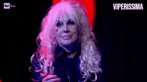 a woman in a wig is applauding on a stage .