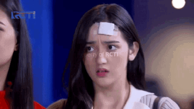 a woman with a bandage on her head is making a funny face .