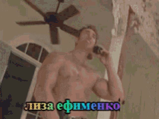 a man without a shirt is talking on a cell phone in russian