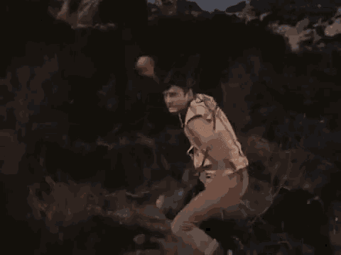 a man is running through a forest with his arms outstretched in a movie .