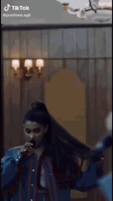 a woman is singing into a microphone in a room with a chandelier .