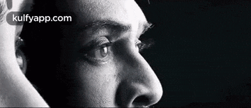 a black and white photo of a man 's face with a woman 's face behind him .