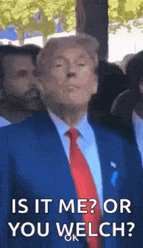 a man in a suit and tie is standing in front of a crowd and asking is it me or you welch ?