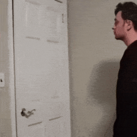 a man in a black shirt is standing in front of a door .