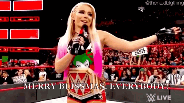 a female wrestler is holding a microphone in front of a crowd and saying merry blissmas everybody .