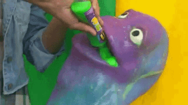 a person is holding a green stick in front of a purple monster