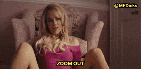 a woman in a pink sweater is sitting in a chair with her legs crossed and says zoom out in yellow letters