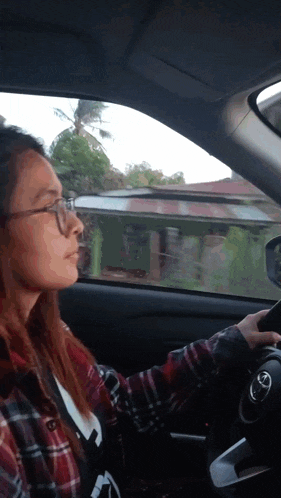 a woman in a plaid shirt is driving a car