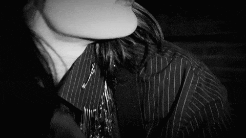 a black and white photo of a man wearing a striped shirt and tie