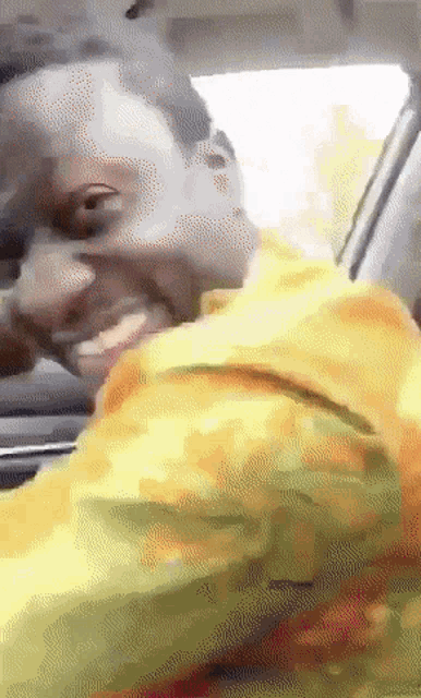 a man in a yellow jacket is looking out of a car window