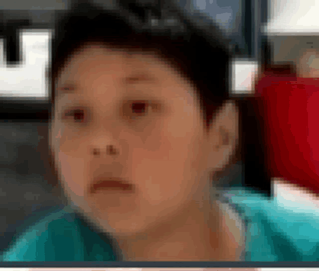 a blurry picture of a young boy 's face with a blue shirt on