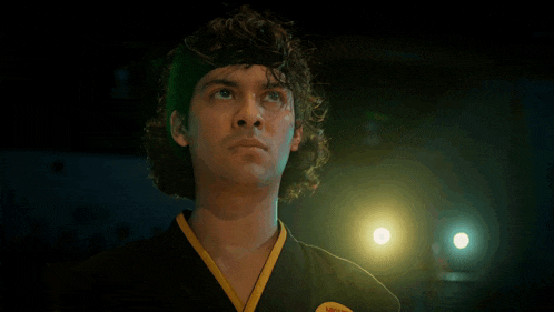 a man in a black and yellow karate uniform has a yellow patch on his chest that says karate