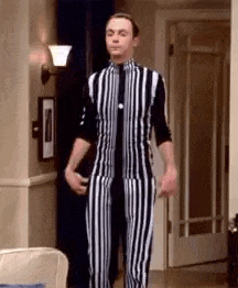 a man is standing in a living room wearing a black and white striped jumpsuit .