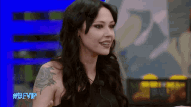 a woman with a tattoo on her arm is smiling in front of a blue background that says #gfvip on it